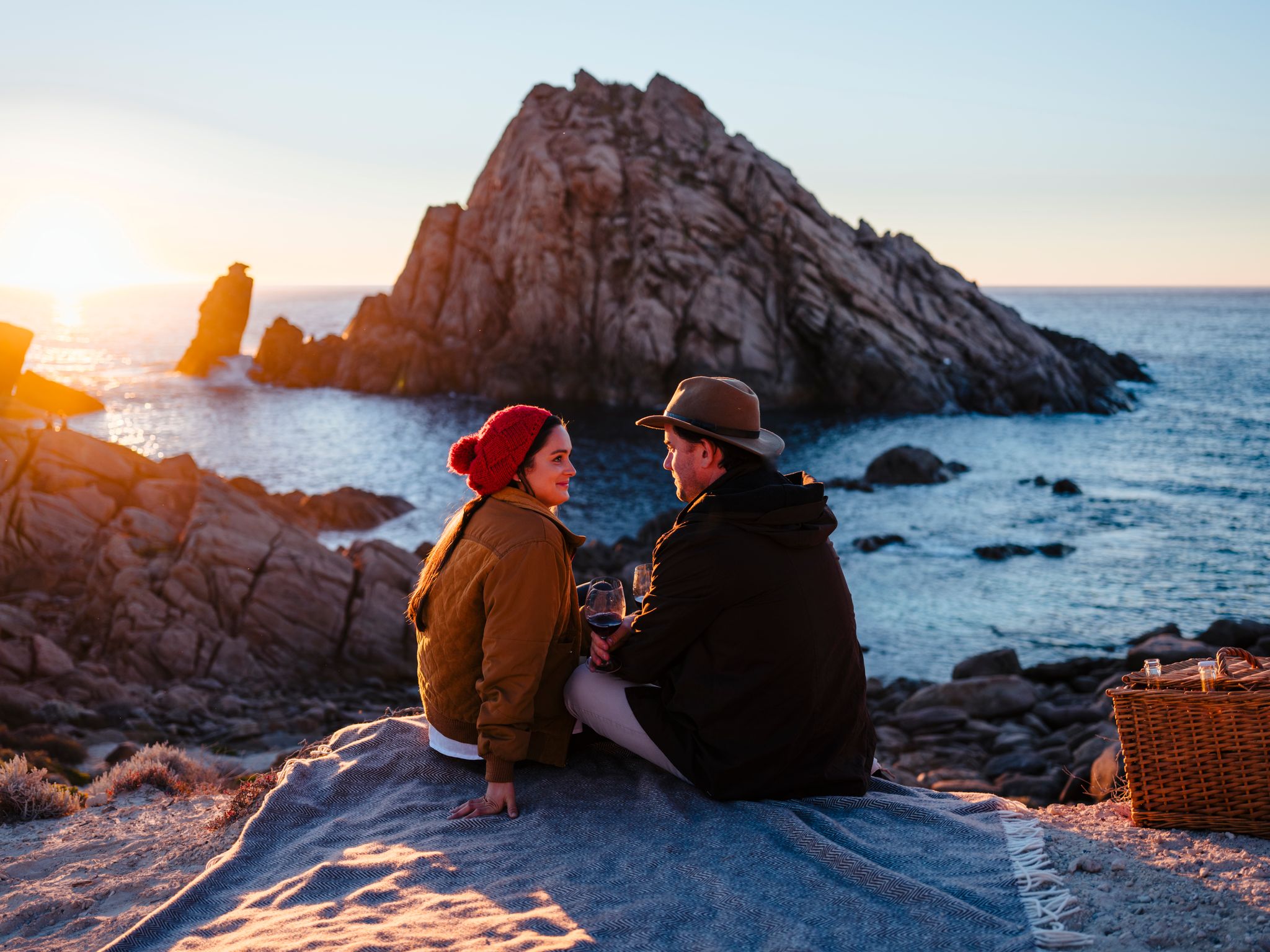 Couple looking at each other as sun sets over Sugar Loaf rock.