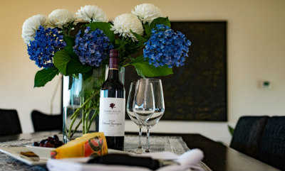 Vase of vibrant blue and white hydrangeas on dining table with Vasse Felix wine and cheeseboard awaiting guests on arrival.